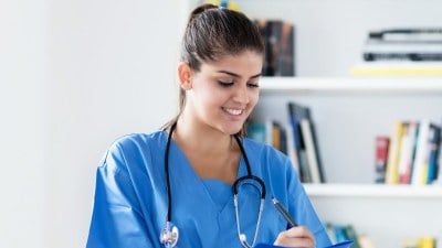 Nursing student taking notes on a clipboard while enrolled in one of the fastest LPN programs.