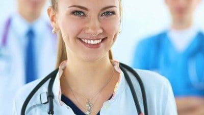 tudent nurse smiling with a stethoscope, working toward her degree in one of the cheapest FNP programs.