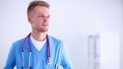 Nurse in scrubs with stethoscope looking ahead, considering a 1 year online DNP program