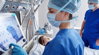 A student in an ABSN program in New York monitoring patient data during clinical training in a hospital setting.
