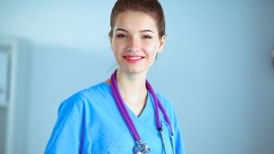 Smiling medical assistant in blue scrubs standing in a clinical setting, representing Florida medical assistant programs.